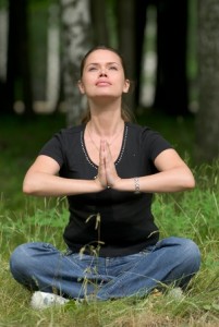 Woman doing yoga exercise on a fresh grass in a park